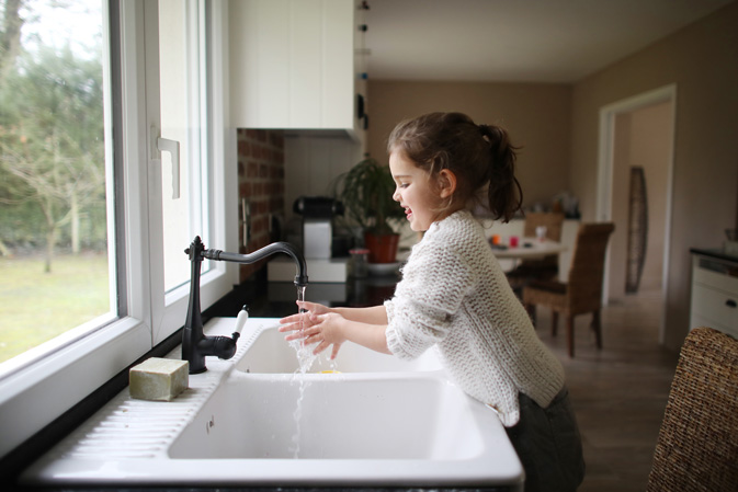 Girl washing her hands with clean water coming out of the sink